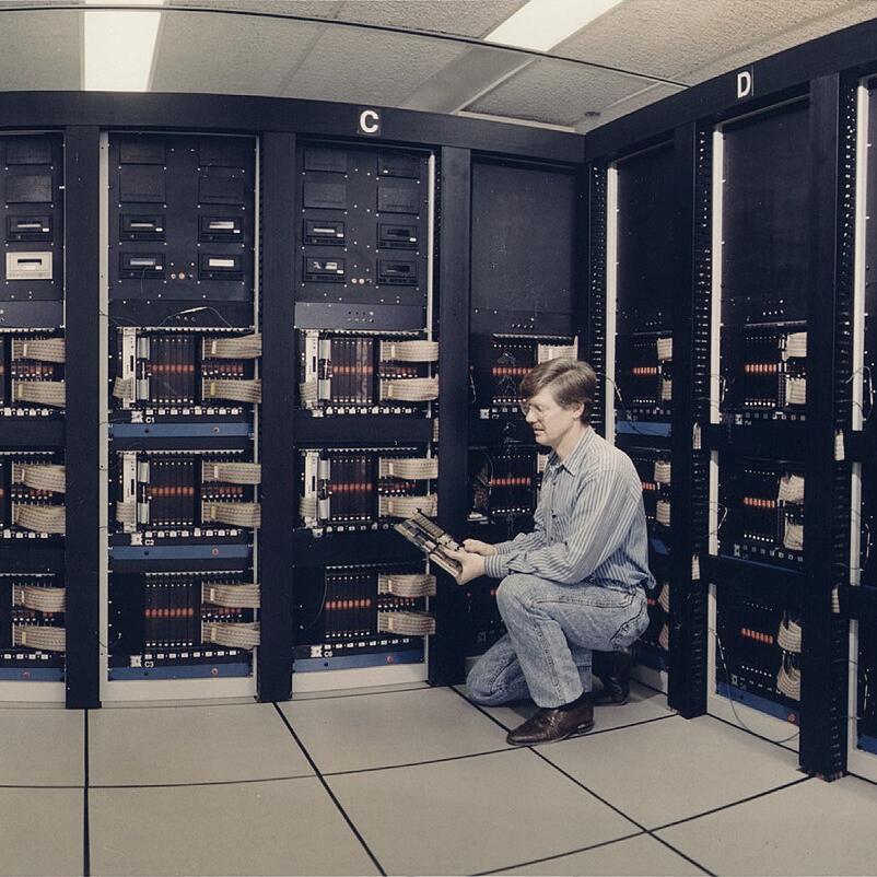 An operator working beside computer cabinets in a historic machine hall